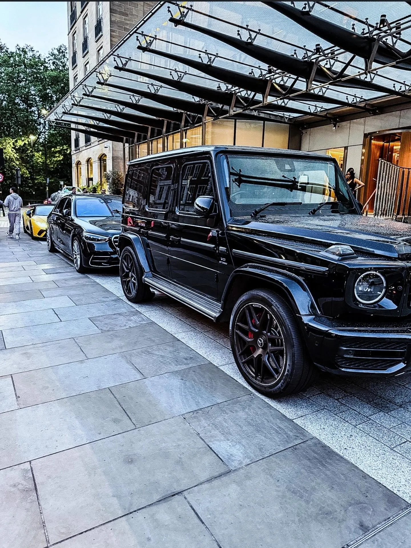 Black Mercedes G-Class parked under a hotel's glass canopy