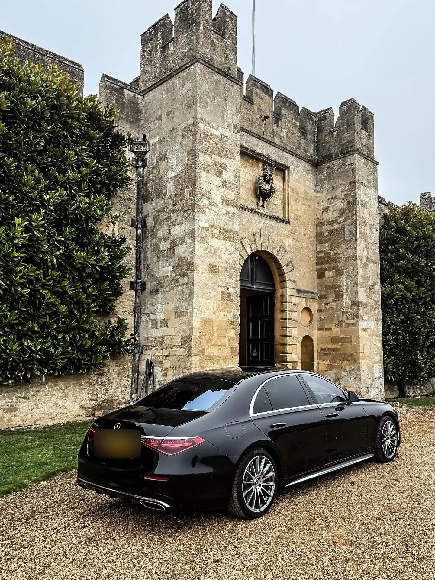 Black Mercedes S-Class parked in front of a stone castle gatehouse
